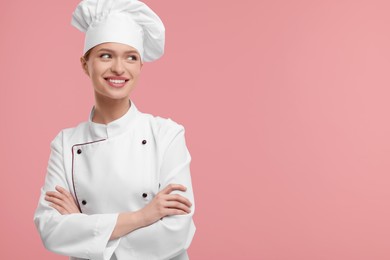 Photo of Happy woman chef in uniform on pink background, space for text