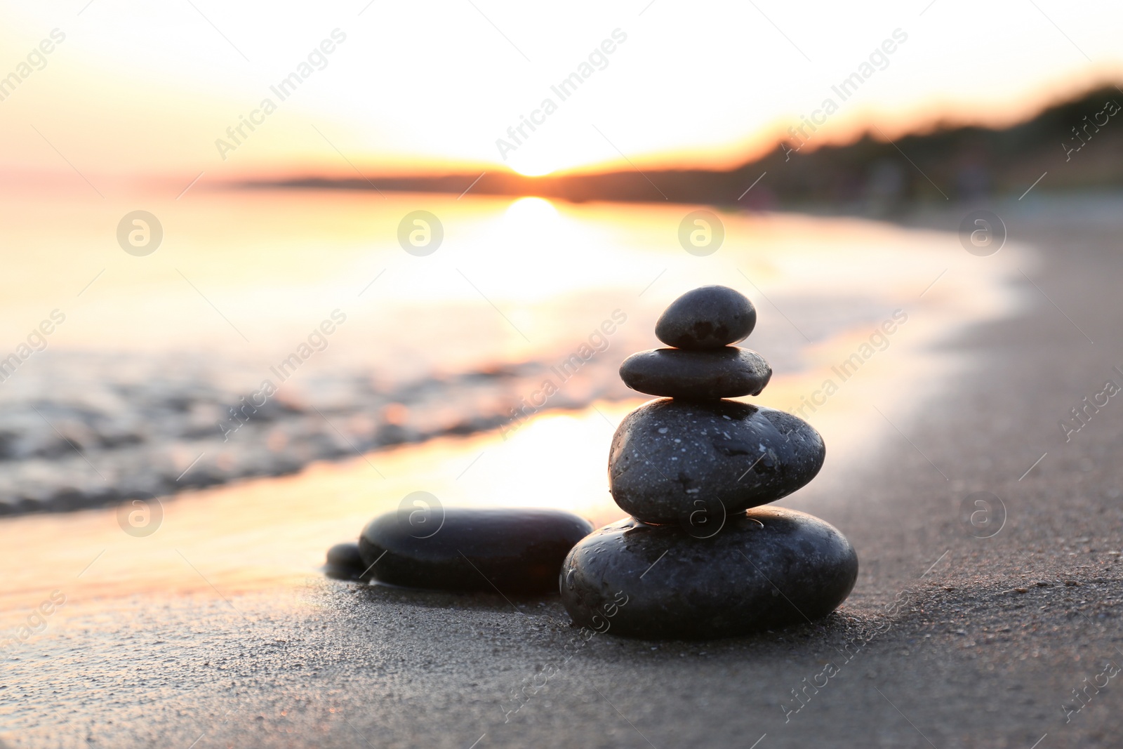 Photo of Dark stones on sand near sea at sunset, space for text. Zen concept