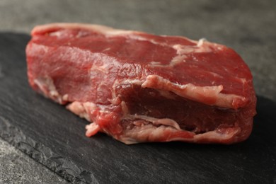 Piece of raw beef meat on grey table, closeup