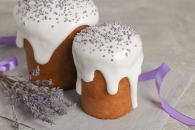 Photo of Tasty Easter cakes and lavender flowers on grey table