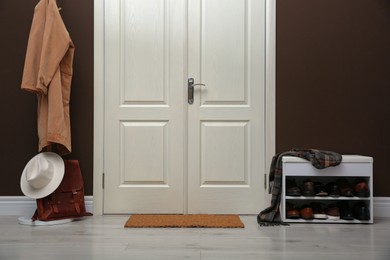 Photo of Shelving unit with shoes, coat rack and door mat in hall