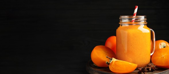 Image of Tasty persimmon smoothie with straw and fresh fruits on table against black background, space for text. Banner design