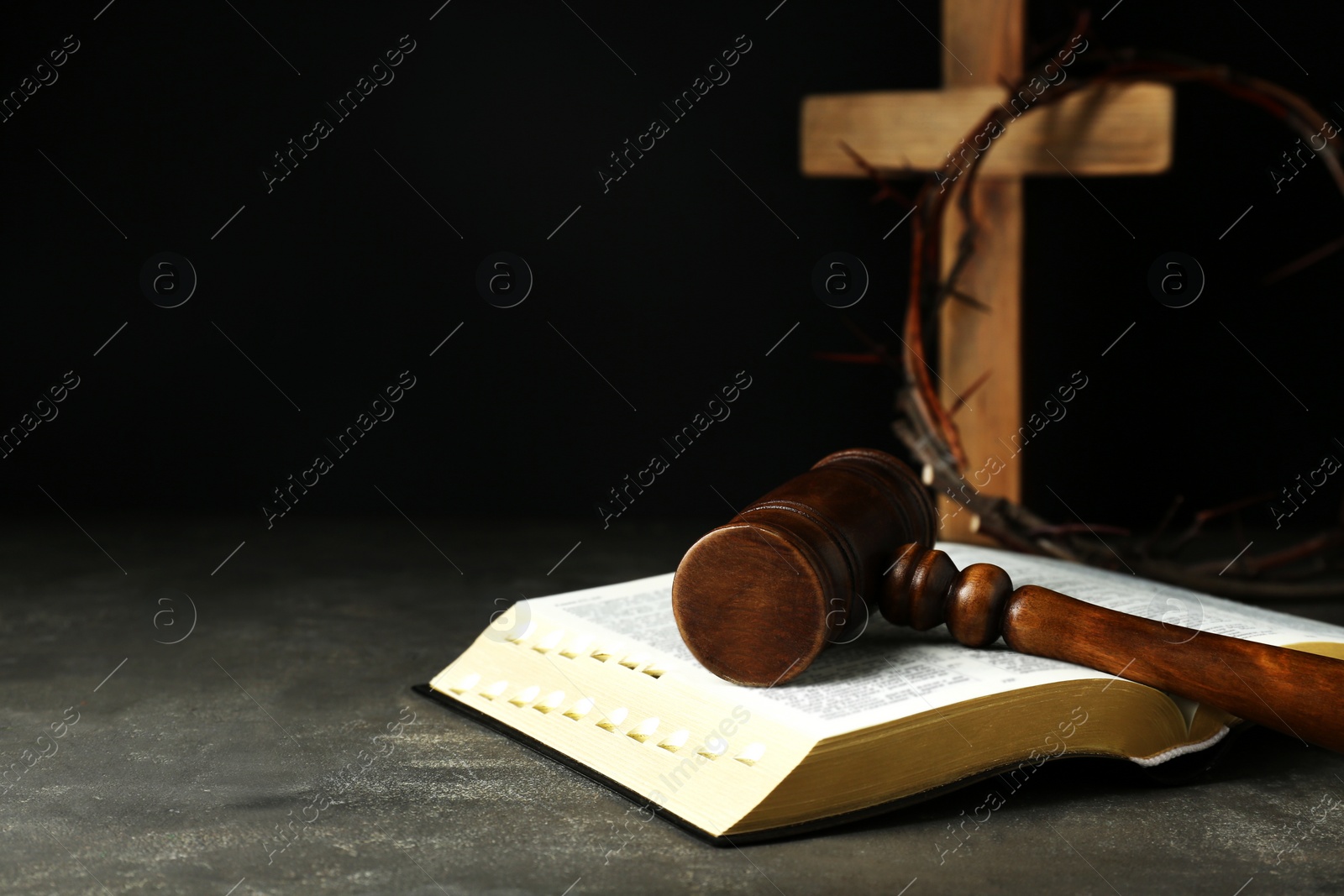 Photo of Judge gavel, bible, wooden cross and crown of thorns on grey table. Space for text