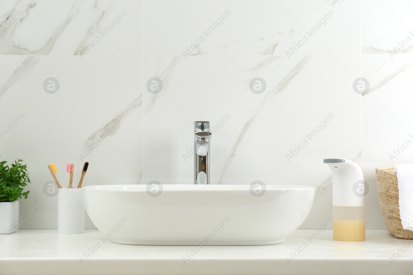 Photo of Modern automatic soap dispenser near sink in bathroom