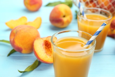 Photo of Natural peach juice and fresh fruits on light blue wooden table, closeup