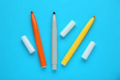 Photo of Different colorful markers and caps on light blue background, flat lay