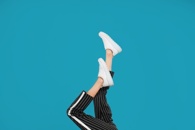 Woman in stylish sport shoes on light blue background