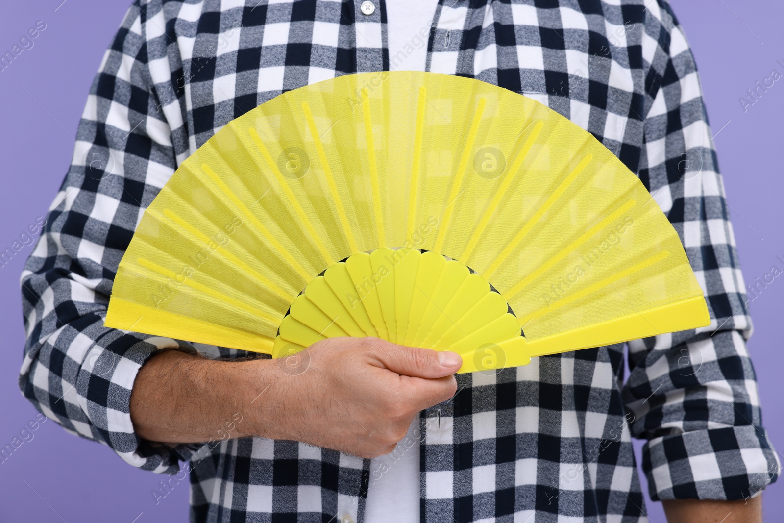 Photo of Man holding hand fan on purple background, closeup