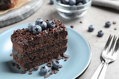 Delicious fresh chocolate cake with blueberries on light table, closeup