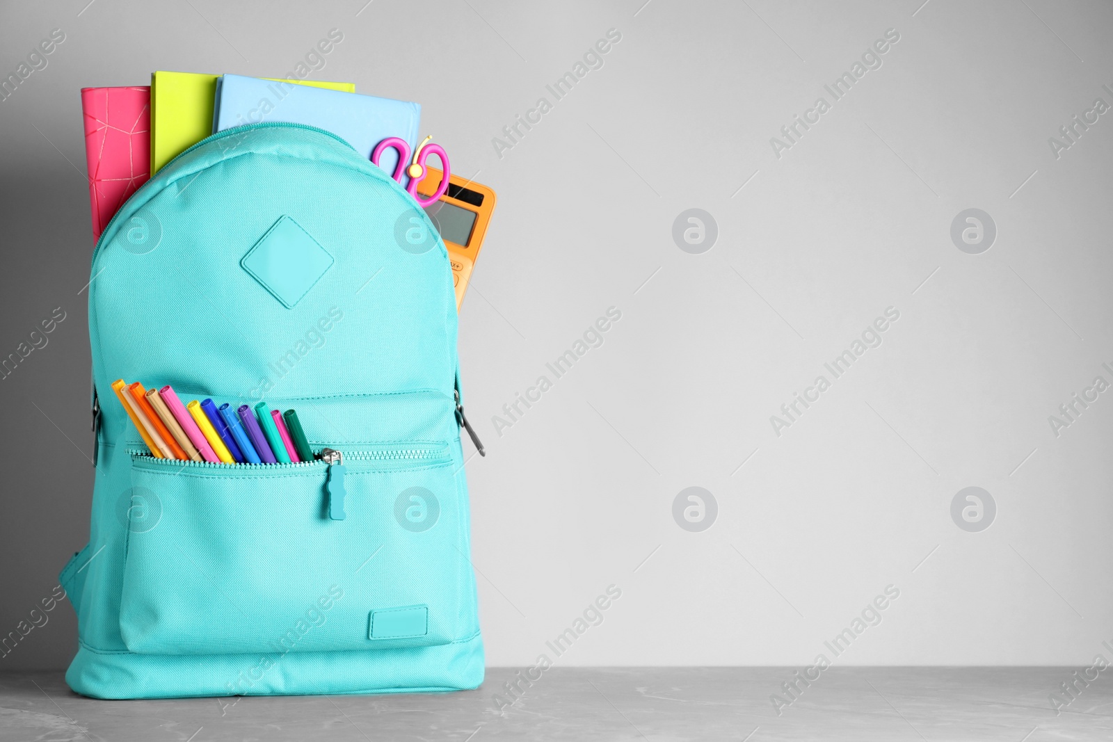 Photo of Stylish backpack with different school stationery on table against light grey background. Space for text