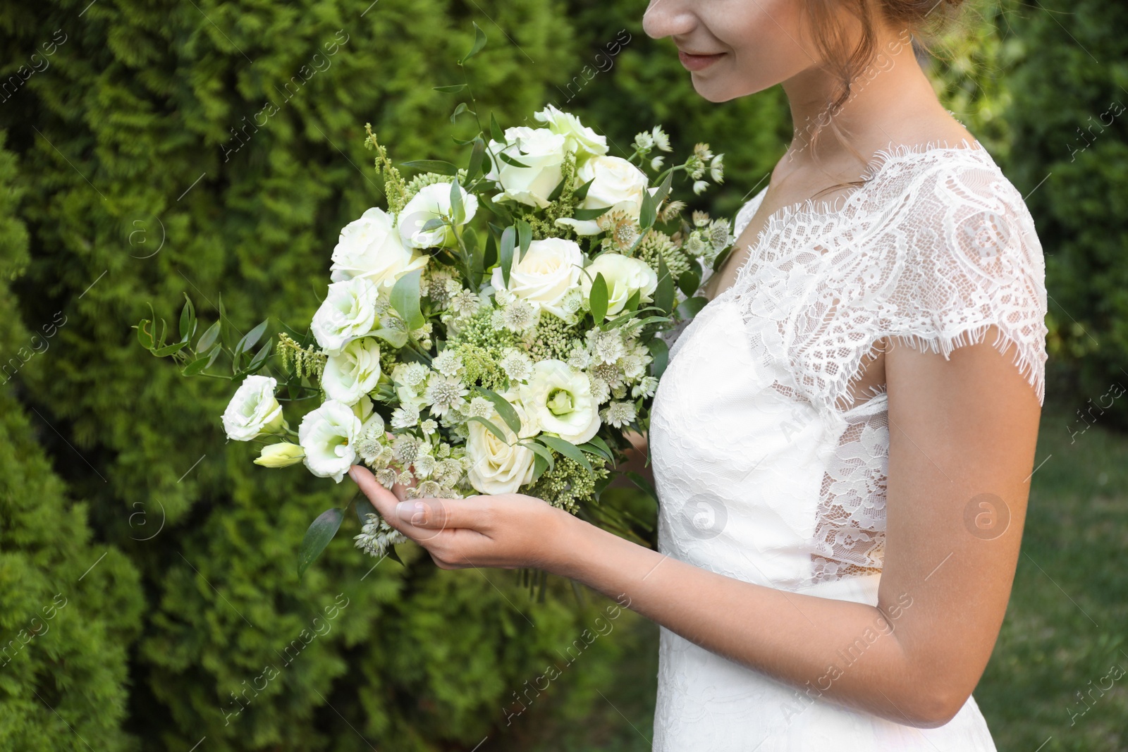 Photo of Bride in beautiful wedding dress with bouquet outdoors, closeup