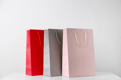 Paper shopping bags on white table against light background