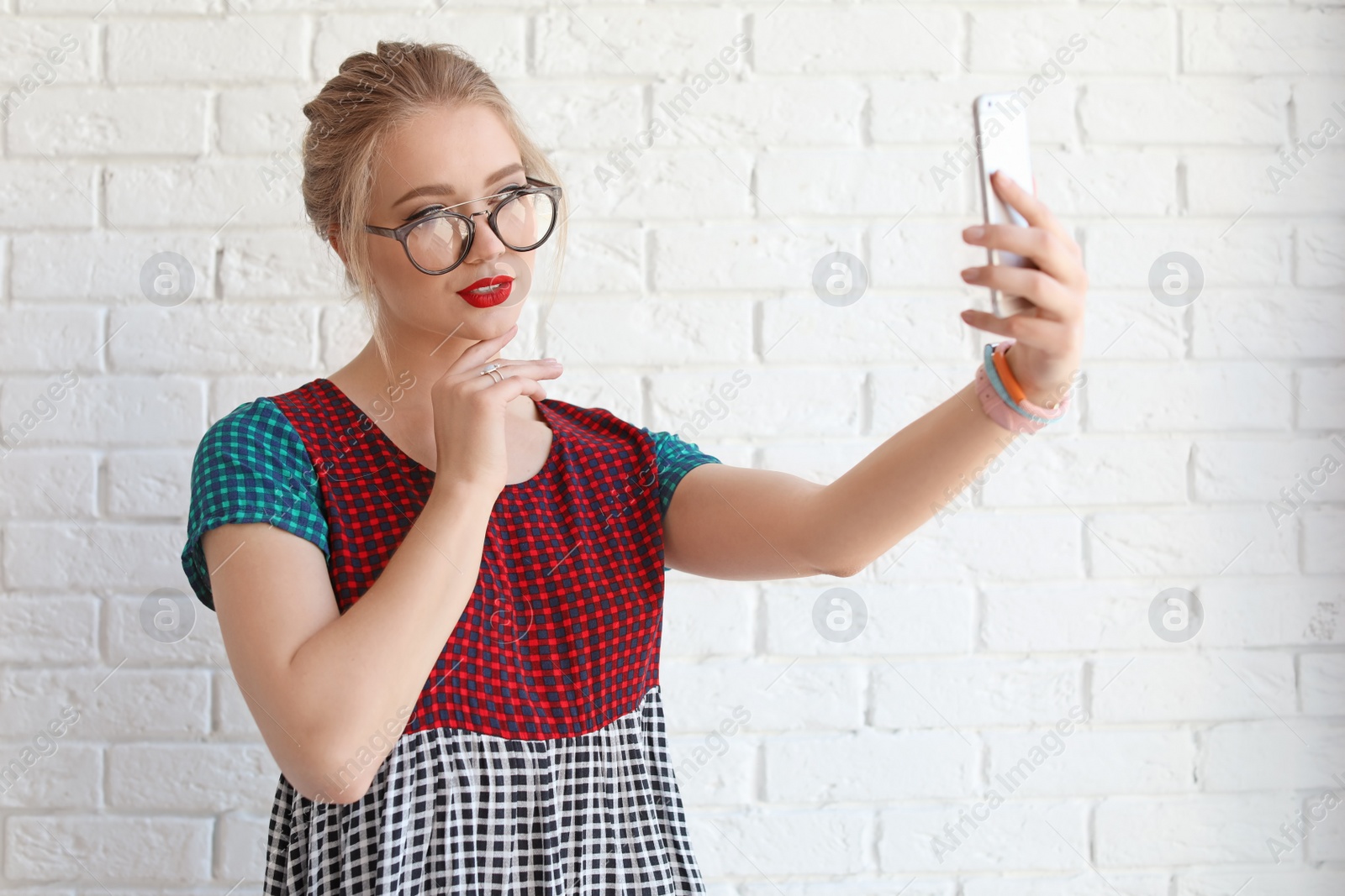 Photo of Attractive young woman taking selfie near brick wall