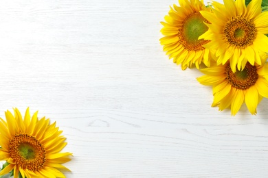 Photo of Yellow sunflowers on wooden background, top view