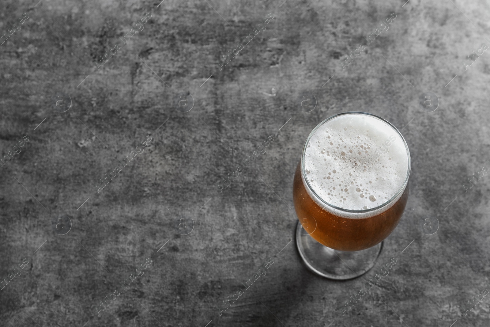 Photo of Glass with cold tasty beer on grunge background, view from above