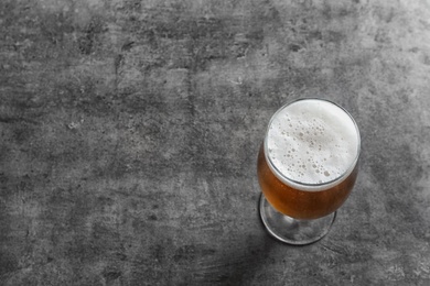 Photo of Glass with cold tasty beer on grunge background, view from above