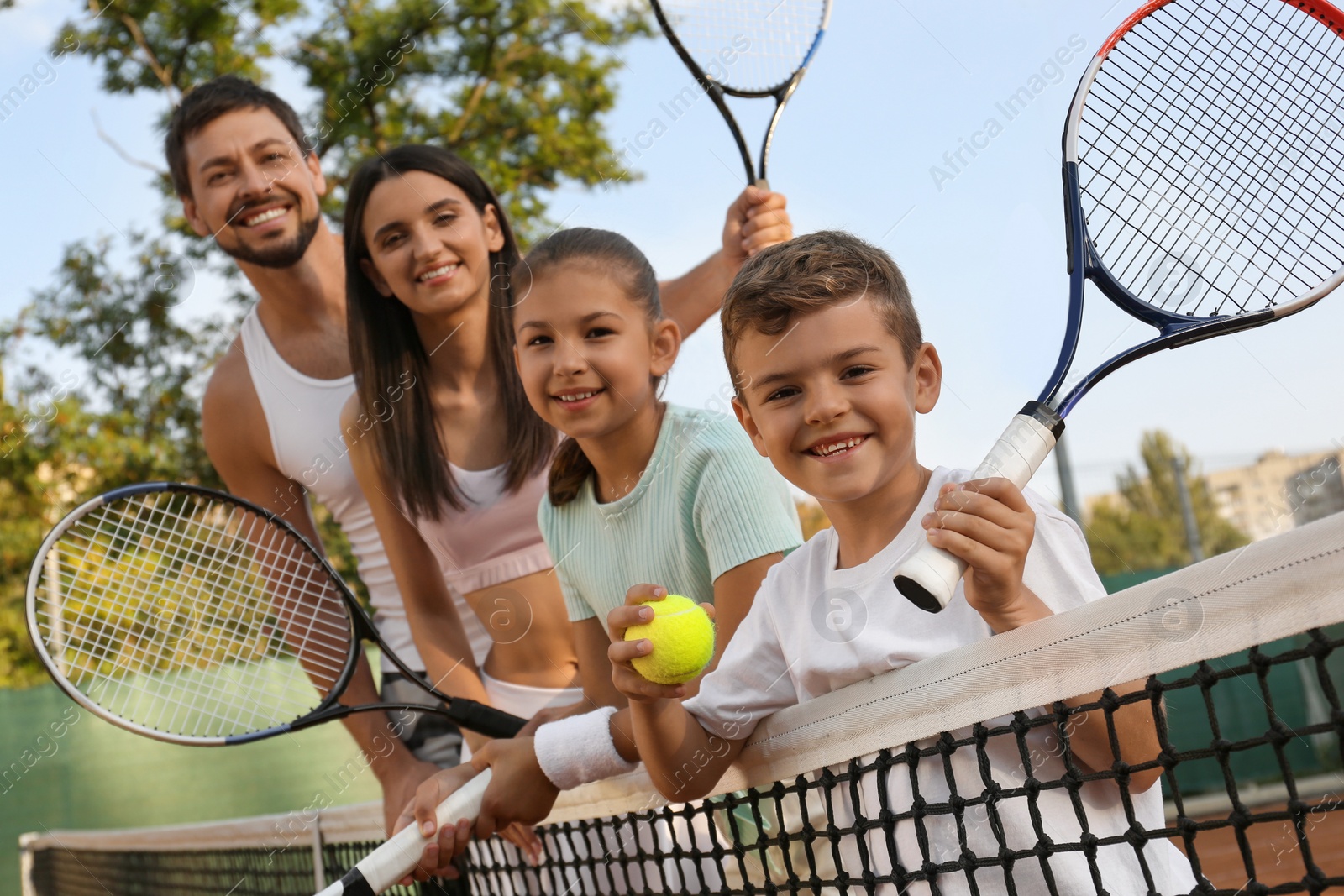 Photo of Happy family with tennis rackets on court outdoors