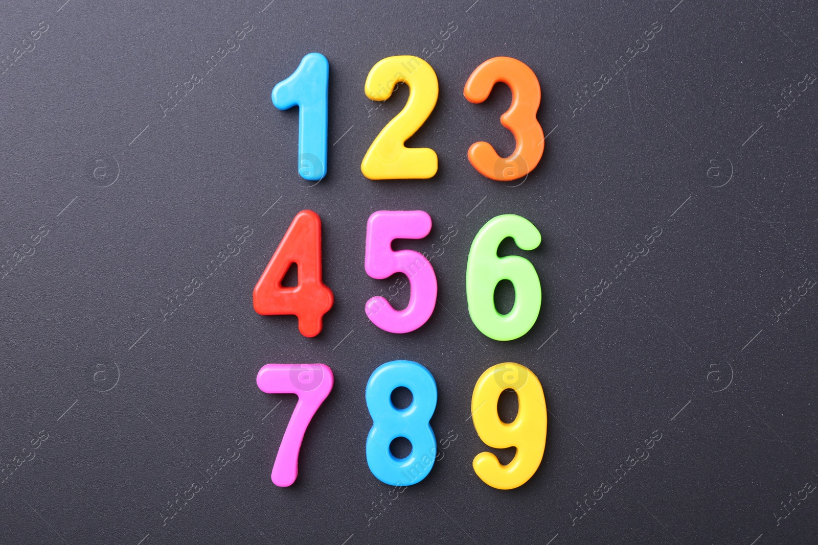 Photo of Colorful numbers on dark gray background, flat lay