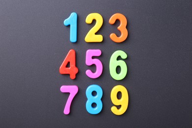 Photo of Colorful numbers on dark gray background, flat lay