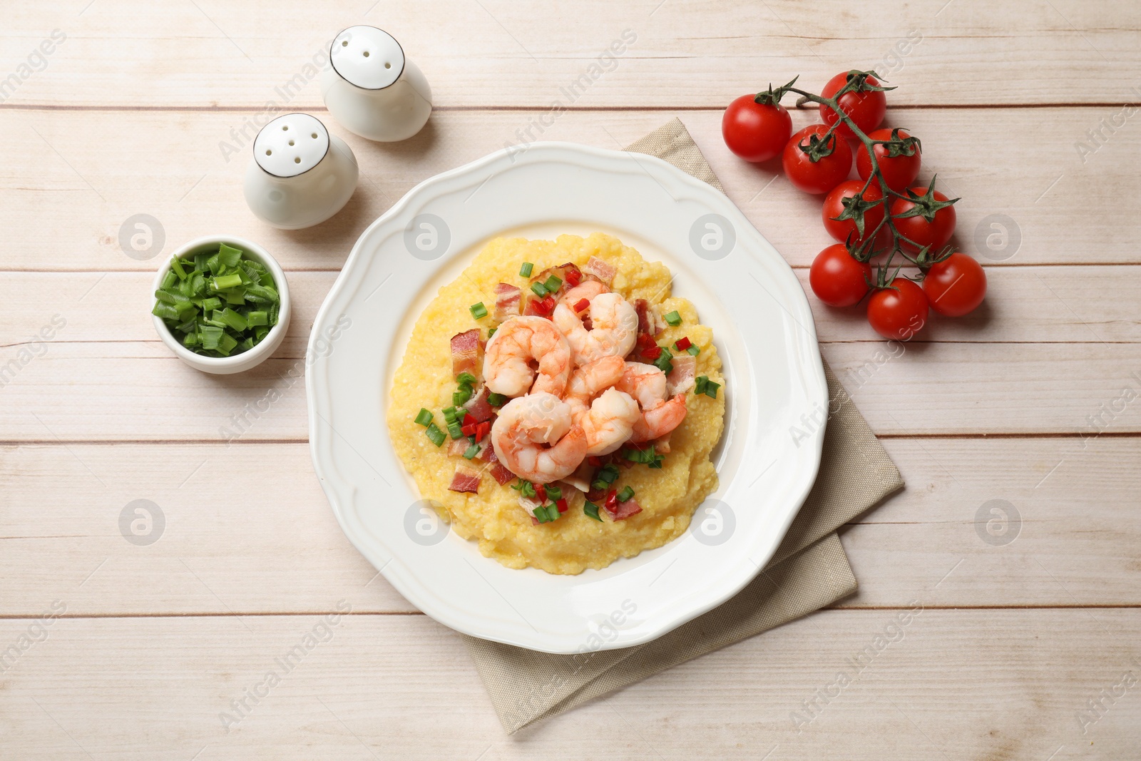 Photo of Plate with fresh tasty shrimps, bacon, grits, green onion and pepper on wooden table, top view