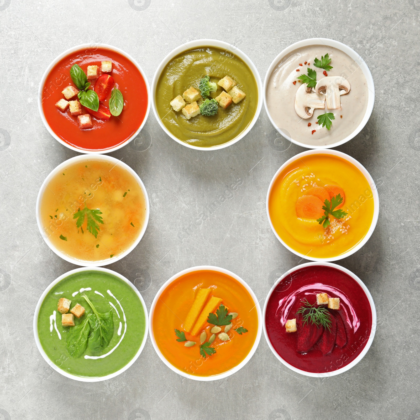 Photo of Various cream soups in bowls and space for text on grey background, top view