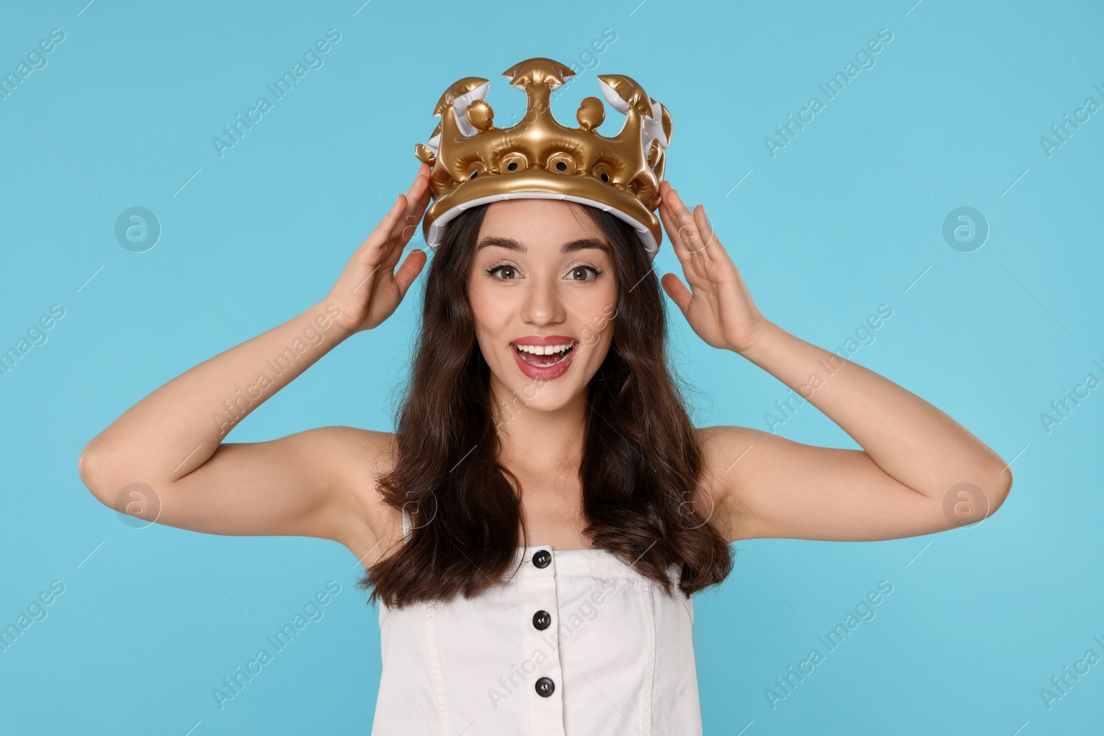 Photo of Beautiful young woman with inflatable crown on light blue background