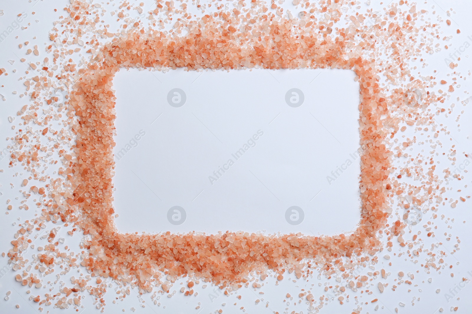 Photo of Frame of pink himalayan salt on white background, top view. Space for text