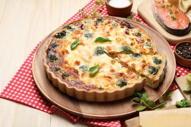 Photo of Delicious homemade quiche and ingredients on table