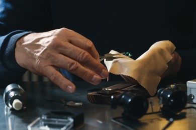 Photo of Professional jeweler working with gemstone at table, closeup