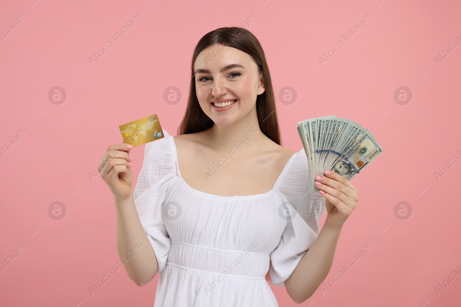 Photo of Happy woman with credit card and dollar banknotes on pink background