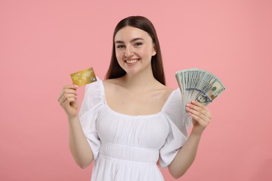 Photo of Happy woman with credit card and dollar banknotes on pink background