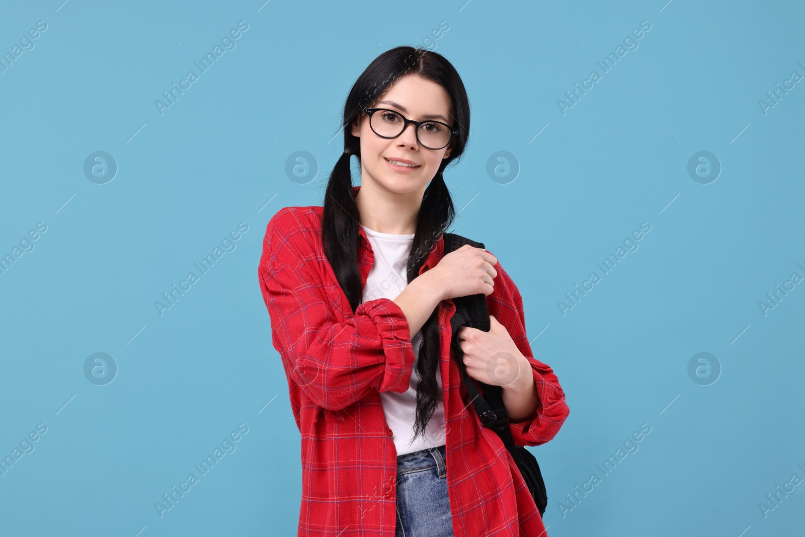 Photo of Smiling student in glasses with backpack on light blue background