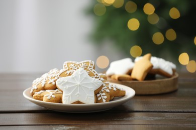 Decorated cookies on wooden against blurred Christmas lights