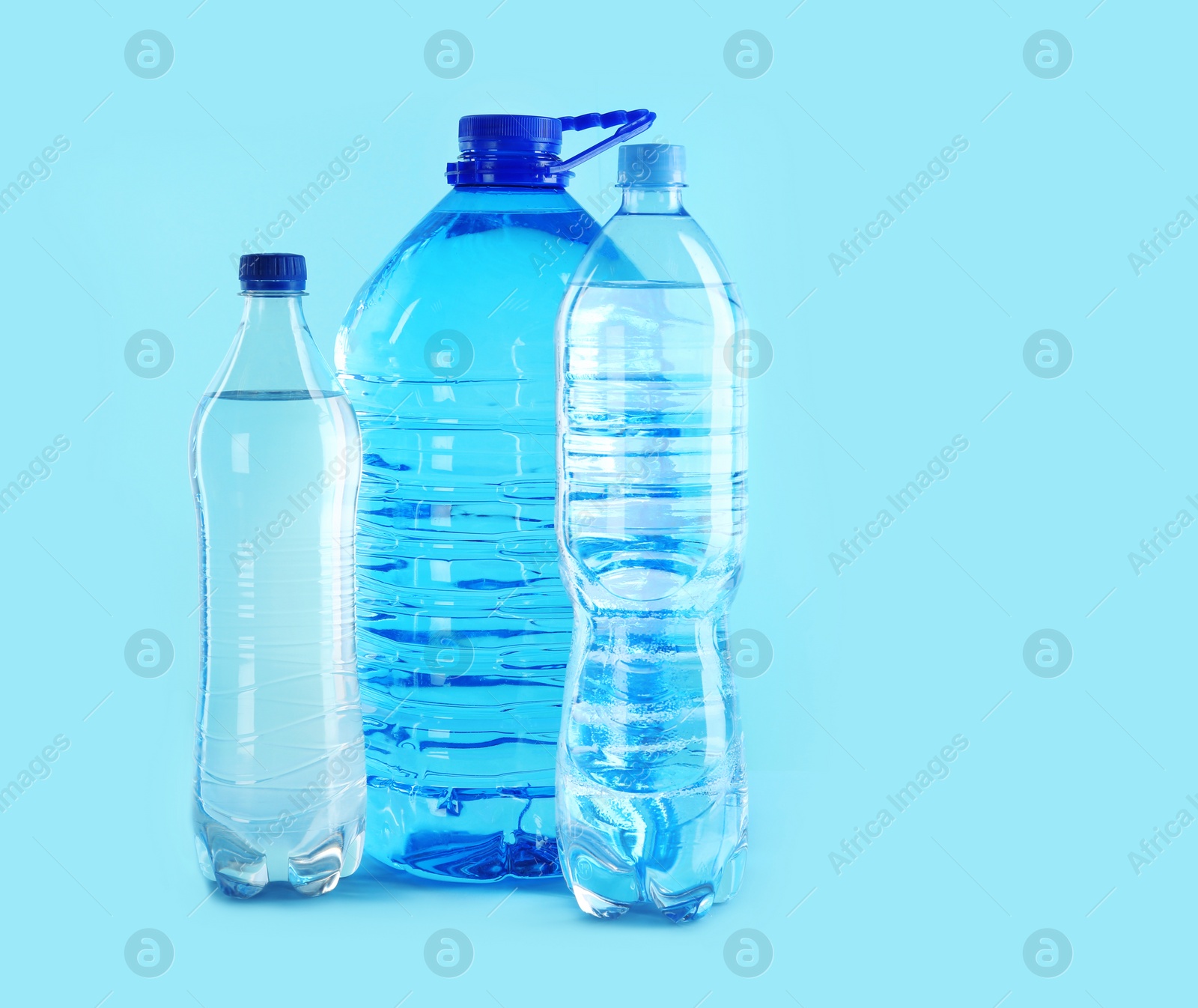 Photo of Different plastic bottles with pure water on color background. Space for text