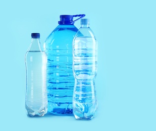 Different plastic bottles with pure water on color background. Space for text