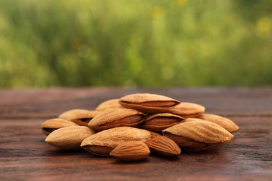 Photo of Almonds on wooden table outdoors, closeup view