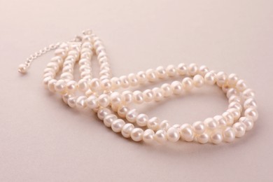 Photo of Elegant necklace with pearls on beige background