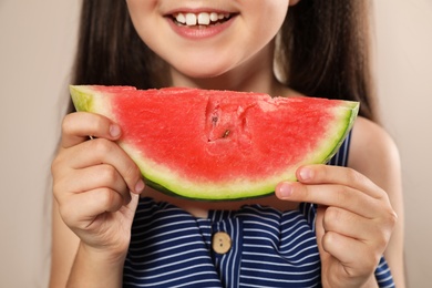 Cute little girl with watermelon on beige background, closeup