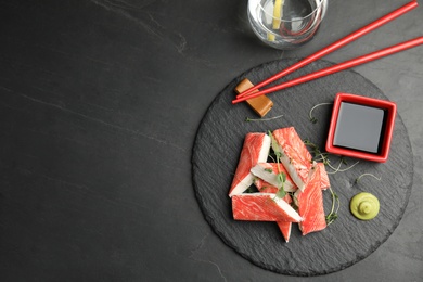 Fresh crab sticks with soy sauce served on black table, flat lay. Space for text