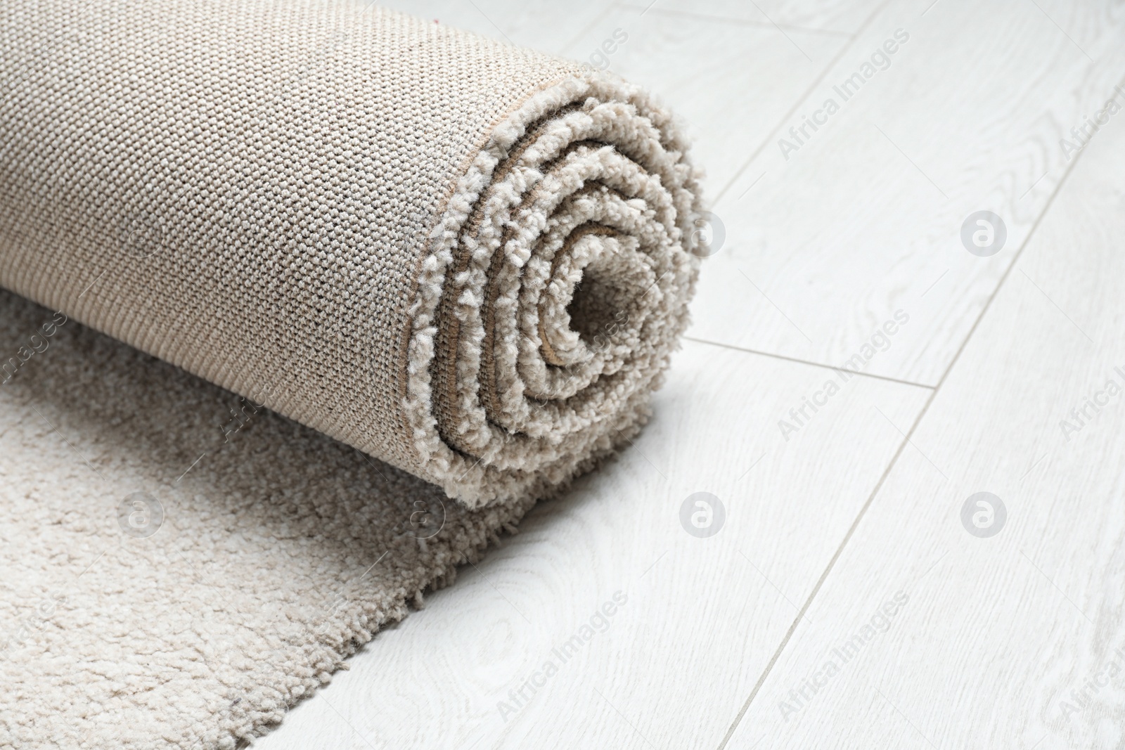 Photo of Rolled fuzzy carpet on wooden background, closeup. Space for text