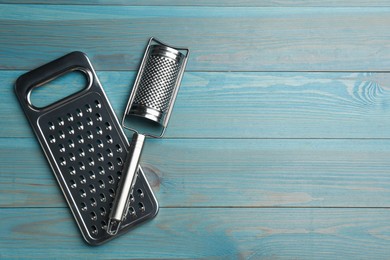 Photo of Modern graters on light blue wooden table, flat lay. Space for text