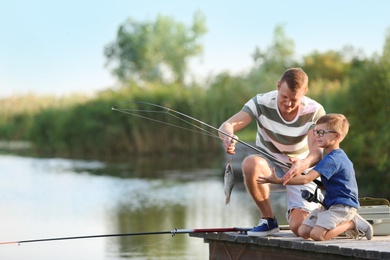 Photo of Dad and son fishing together on sunny day