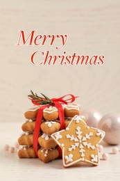 Image of Greeting card with phrase Merry Christmas. Tasty cookies and festive decor on white wooden table