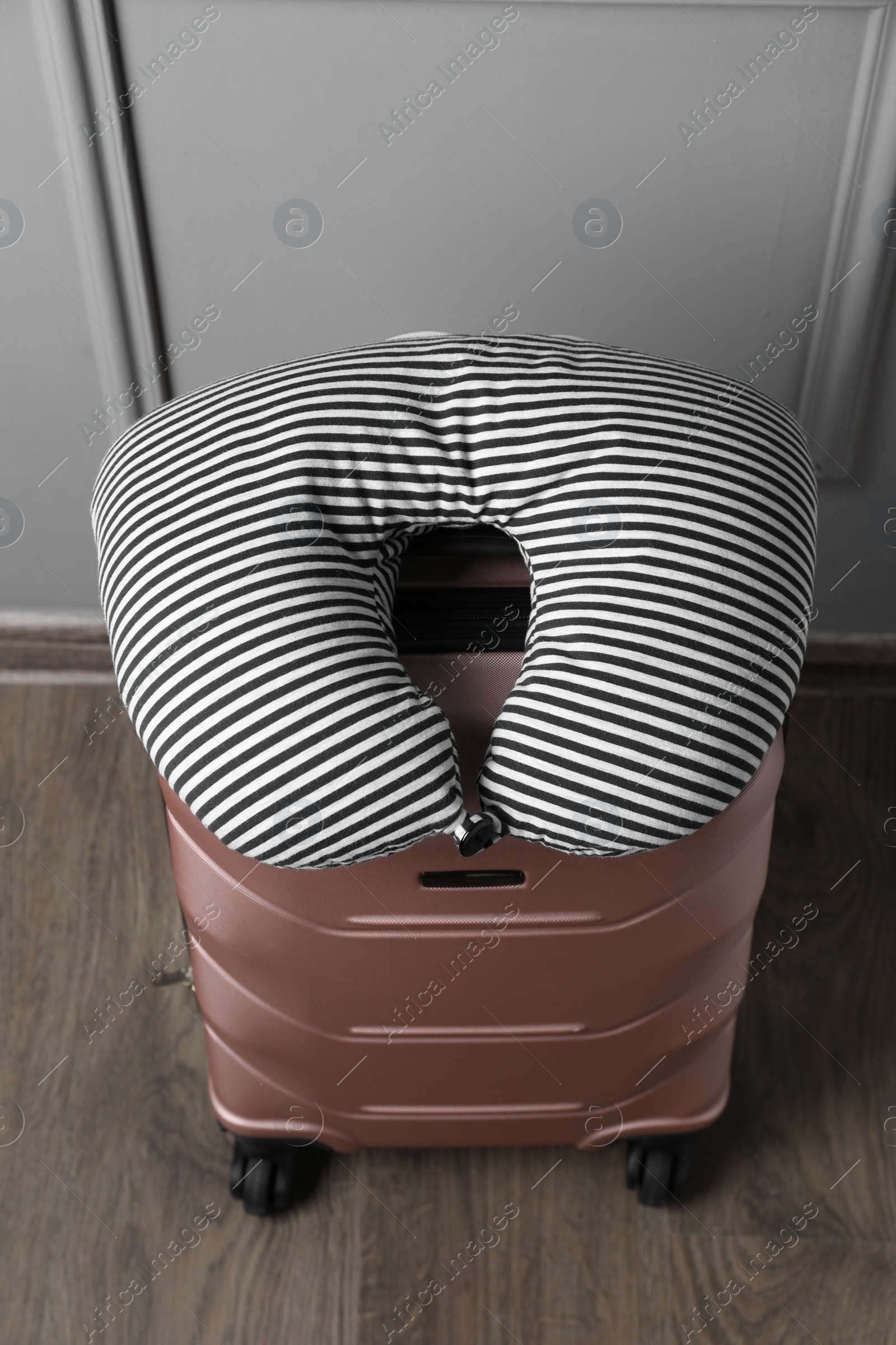 Photo of Striped travel pillow on suitcase near light wall indoors, above view