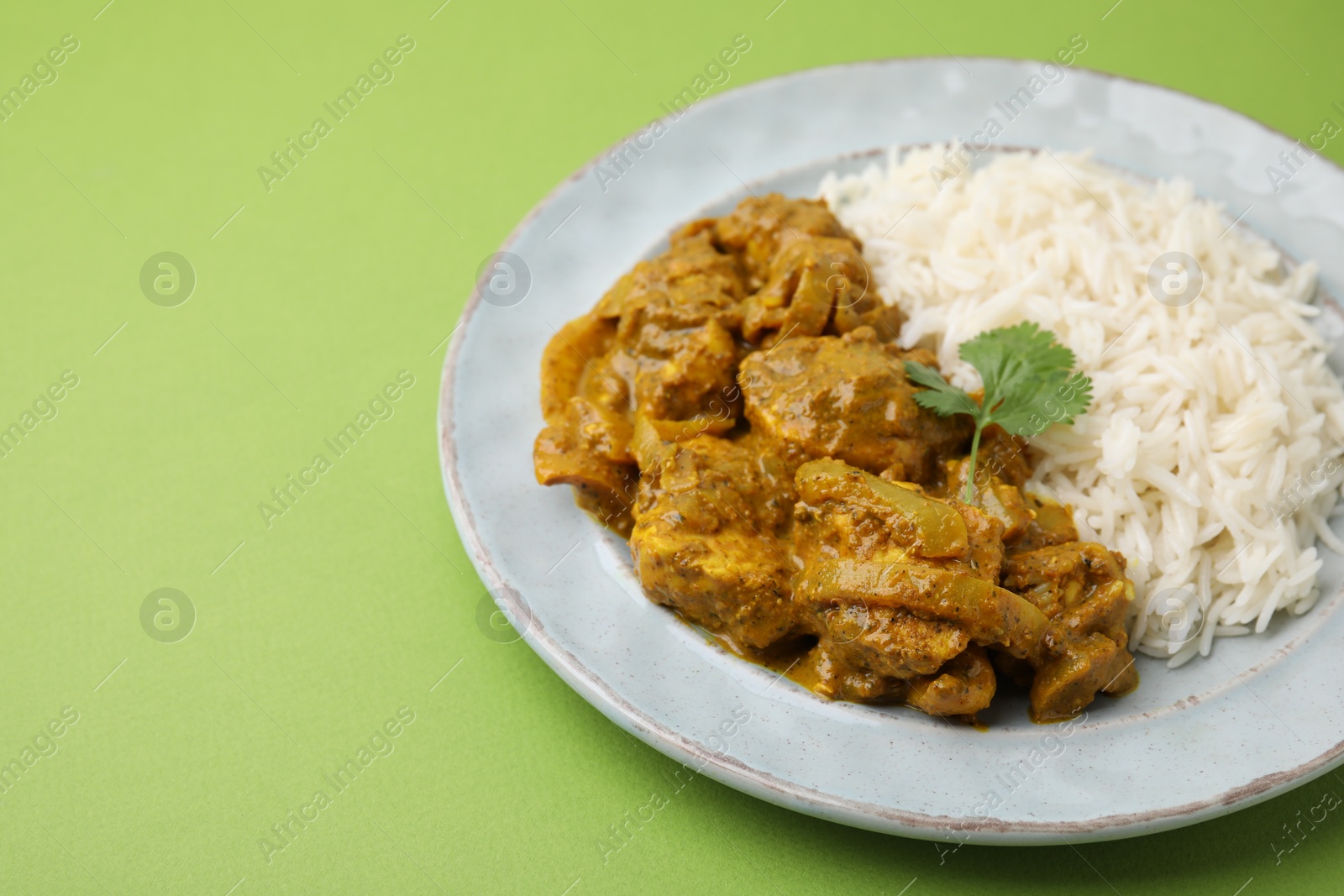 Photo of Delicious chicken curry with rice on green background, closeup