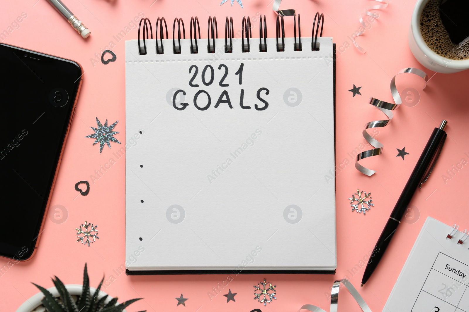 Photo of Flat lay composition with notebook and festive decor on pink background. Goals for New Year 2021