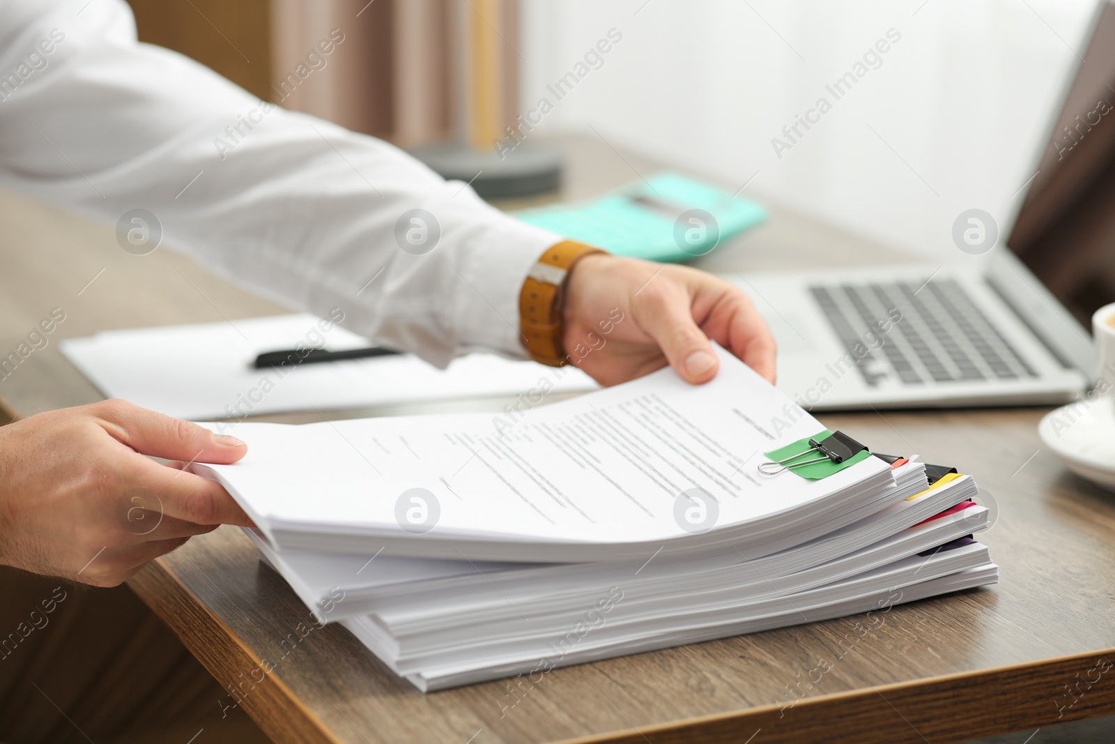 Photo of Man working with documents at wooden table in office, closeup