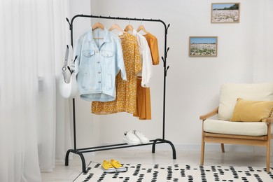 Photo of Stylish showroom interior with clothing rack and armchair