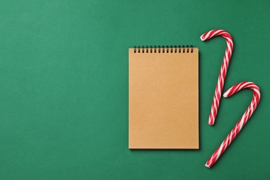 Notebook and candy canes on color background, top view. Christmas countdown