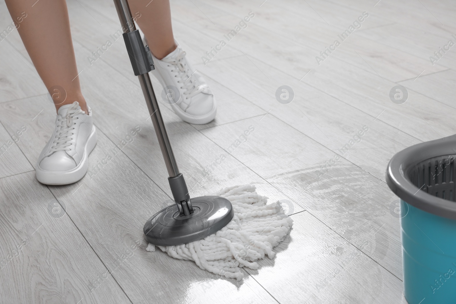 Photo of Woman cleaning floor with mop indoors, closeup